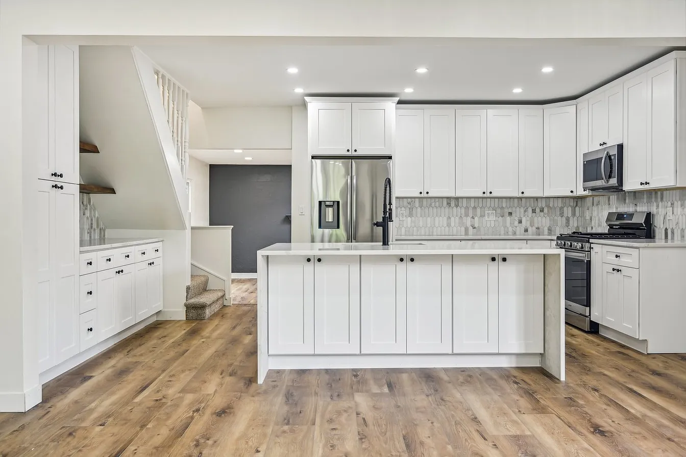 Remodeled Libertyville kitchen seen from the dining area, with a quartz waterfall island, white shaker cabinetry, and wood-look flooring