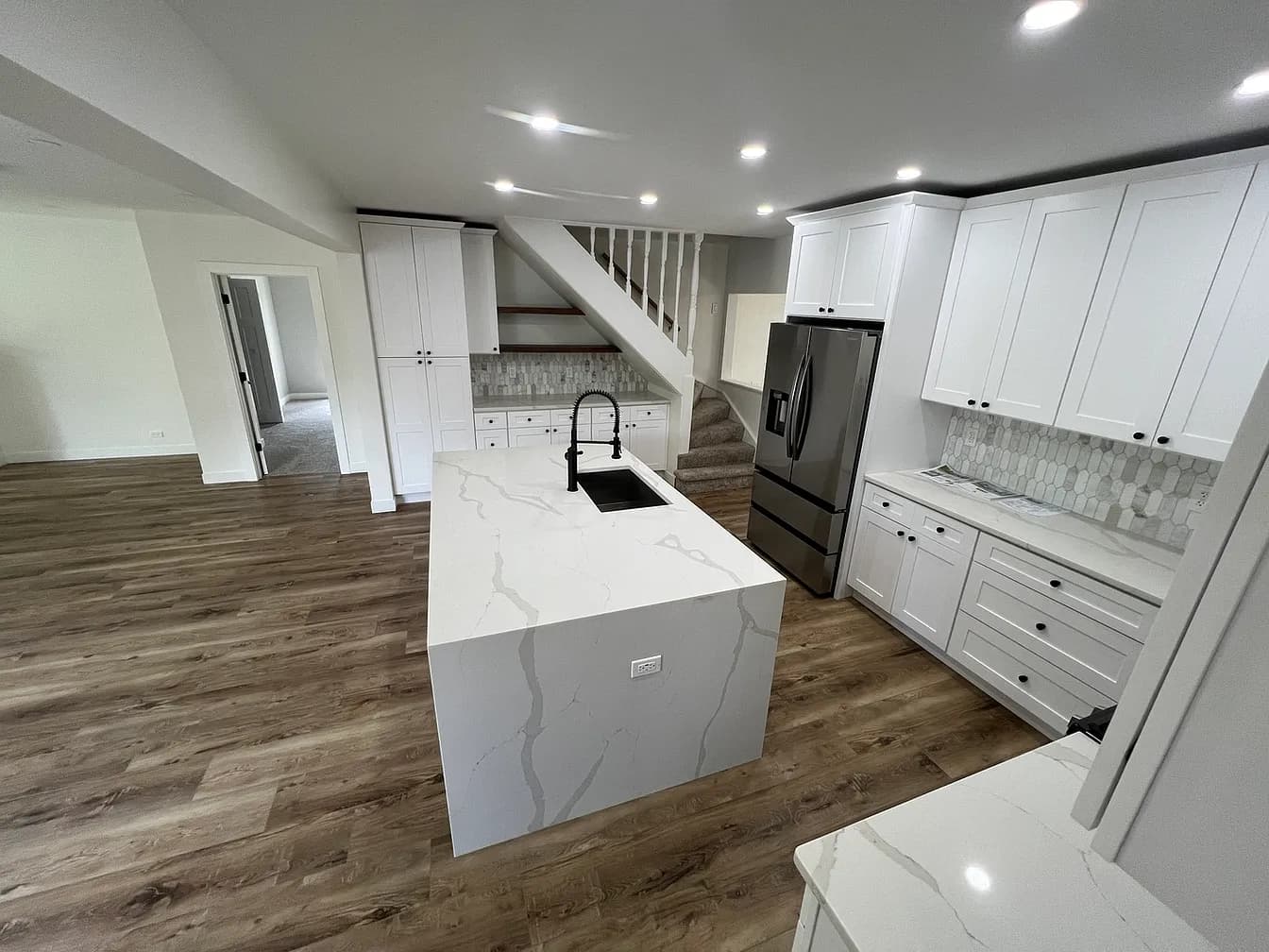 Quartz waterfall island and stainless refrigerator with a marble-look backsplash in the finished Libertyville kitchen remodel