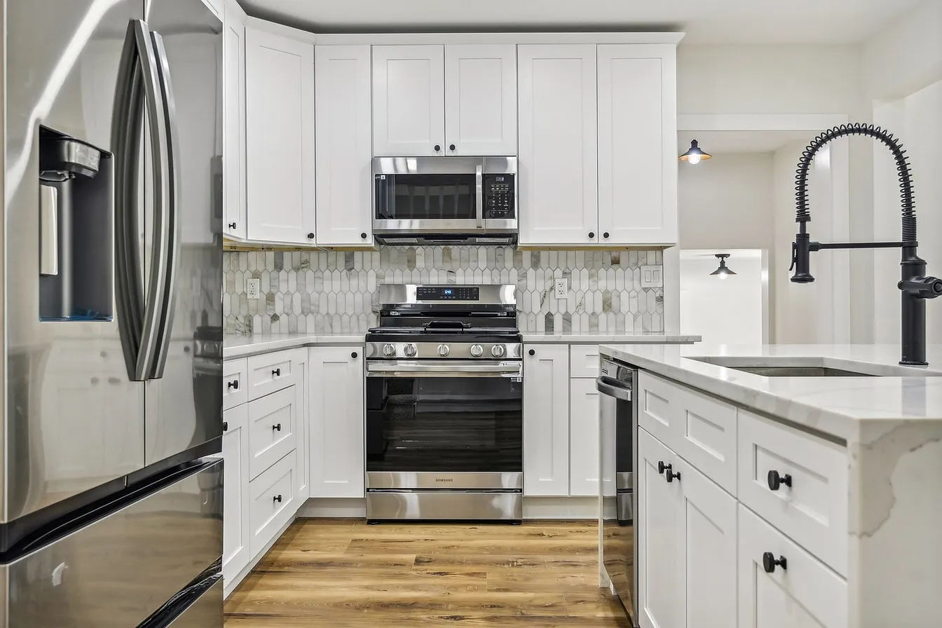 Stainless gas range and over-range microwave set against a full-height marble-look picket tile backsplash in the Libertyville kitchen